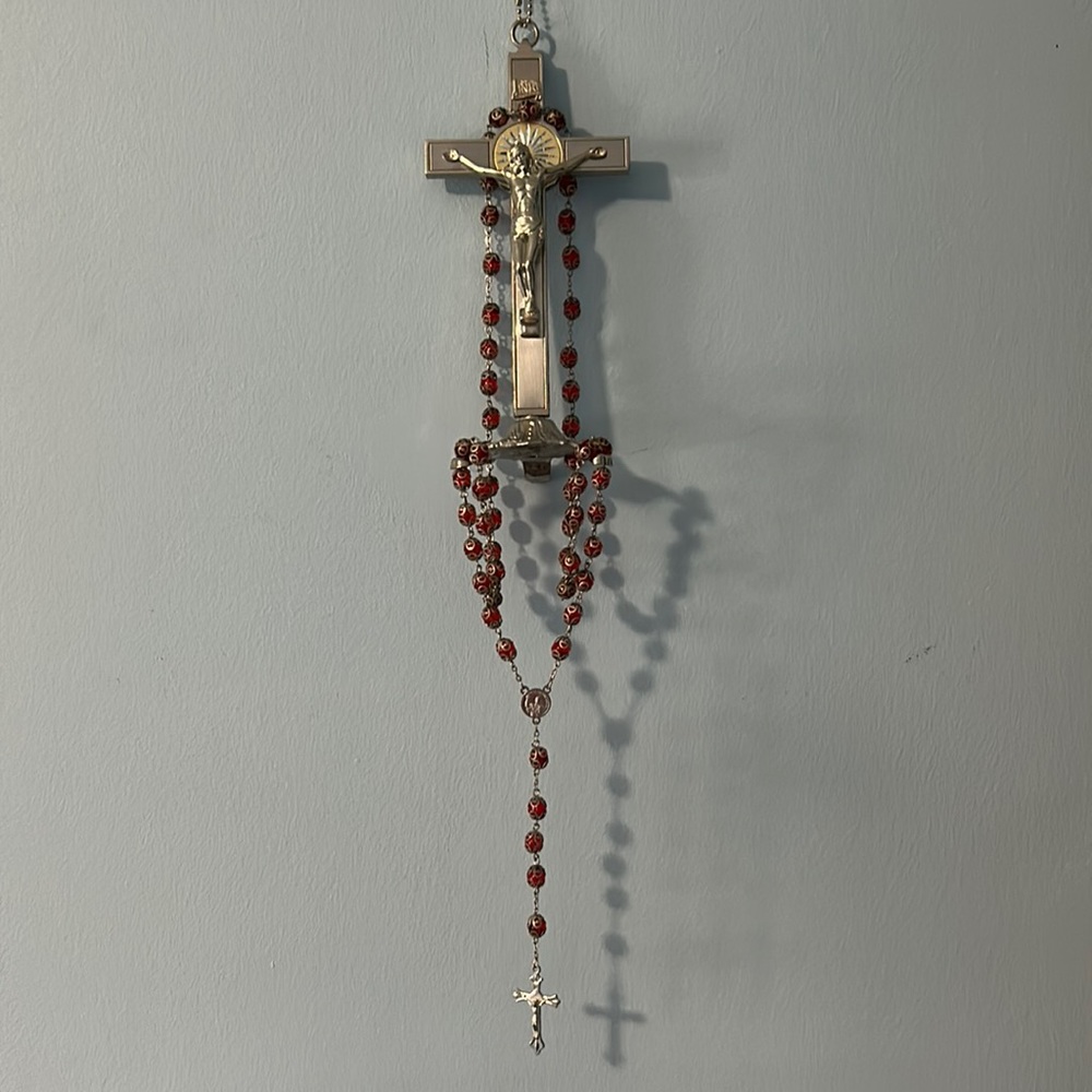 Standing silver crucifix and red glass rosary beads.